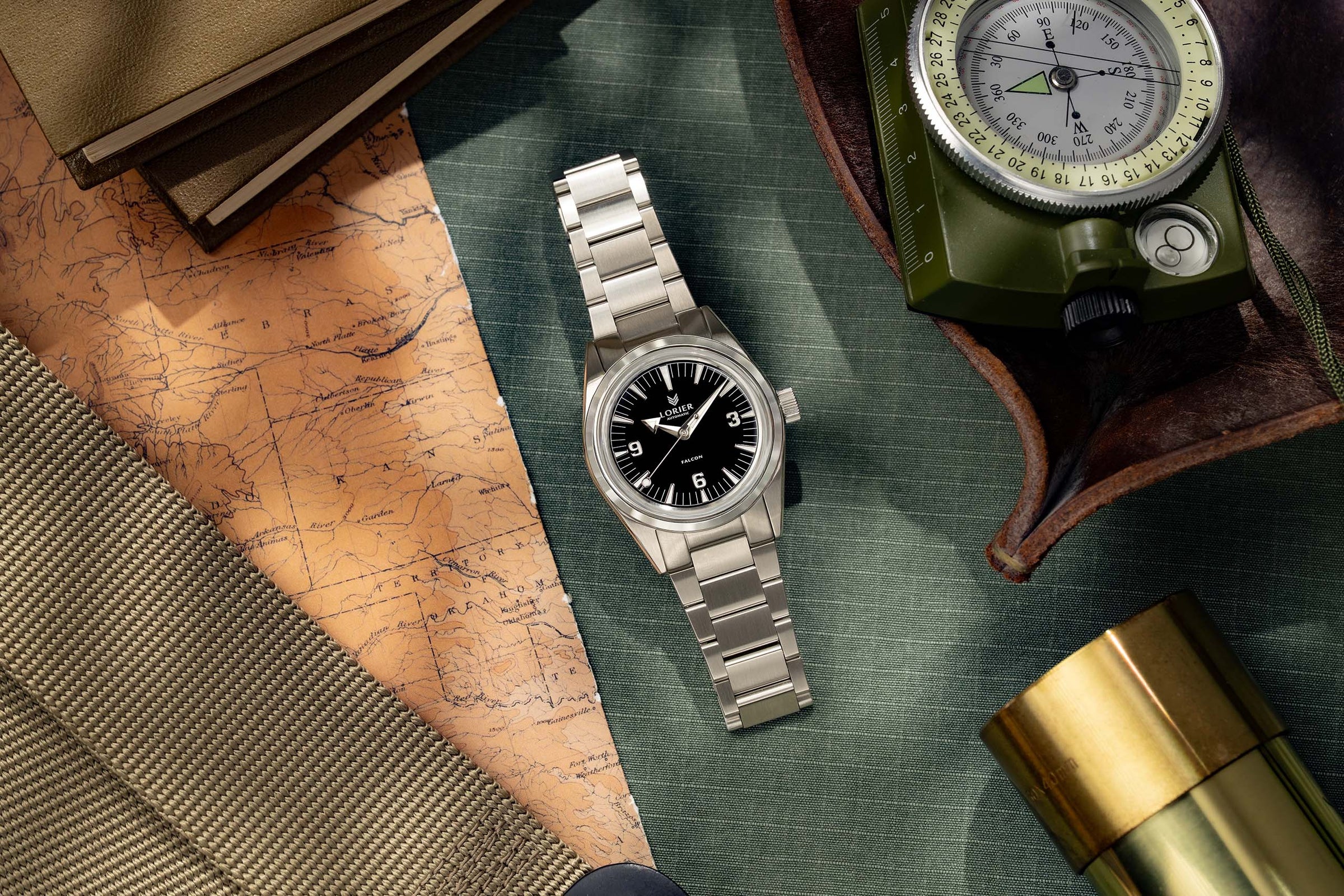 Lorier Neptune dive watch flatlay on grey leather surface with vintage nautical depth chart, U.S. Divers consumer catalog, and open antique brass surveying compass on aged craft paper.
