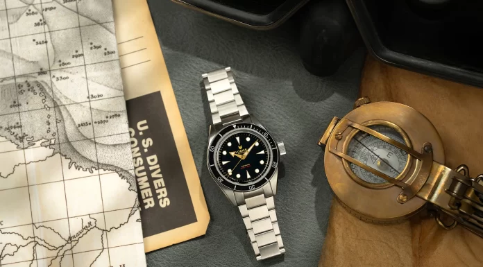 A Lorier visszahozza az Astrát, Falcont, Neptune-t és Hyperiont Lorier Neptune dive watch flatlay on grey leather surface with vintage nautical depth chart, U.S. Divers consumer catalog, and open antique brass surveying compass on aged craft paper.