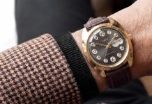 Timex 1976 Rotary Phone Dial Reissue: tárcsás telefon a csuklón Timex® 1976 Rotary Phone Dial Reissue with a gold-tone case, black dial, and brown leather strap worn on the wrist with a patterned blazer.