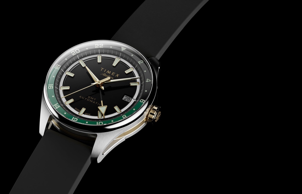 Timex Atelier GMT Première M1a: 38 milliméterben tér vissza a márka GMT-je Timex Atelier GMT Première M1a watch with a black dial, green 24-hour scale, gold-tone accents, and black rubber strap.
