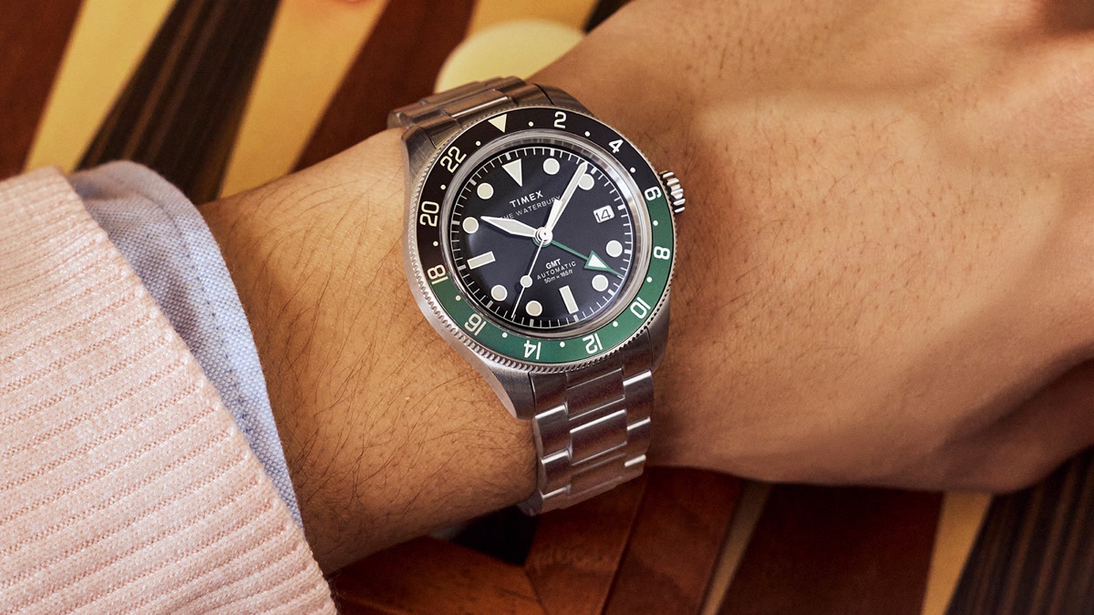 Timex Waterbury Heritage Automatic GMT watch worn on wrist with stainless steel bracelet and green-black bezel.