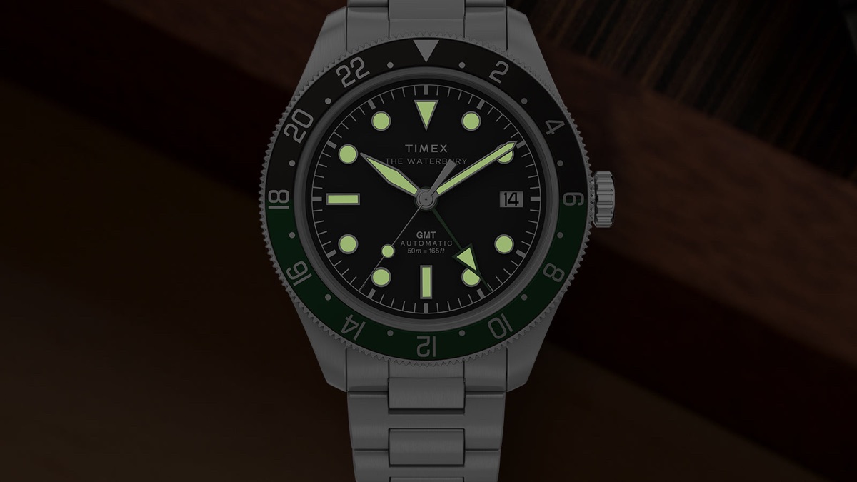 Timex Waterbury Heritage Automatic GMT watch with glowing luminous hands and hour markers in low light.