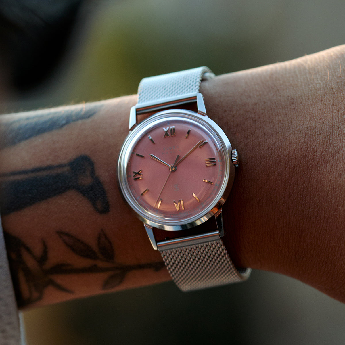 Timex x Todd Snyder Marlin Mesh: a hatvanas évek Marlinja hálós szíjjal tér vissza Close-up of the Todd Snyder x Timex Marlin® Mesh watch with a pink dial and stainless steel mesh bracelet worn on the wrist.