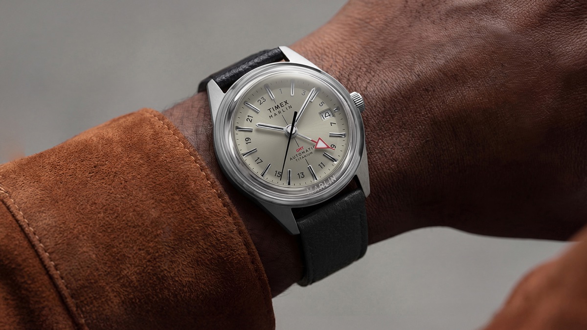 Timex Marlin Jet Titanium Automatic GMT: retrofuturisztikus tok, titánból Marlin® Jet Titanium Automatic GMT watch with cream dial and black leather strap worn on the wrist with a brown suede jacket.