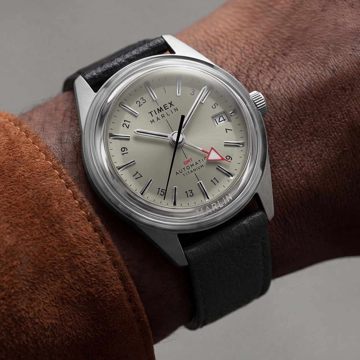 Timex Marlin Jet Titanium Automatic GMT: retrofuturisztikus tok, titánból Close-up of the Marlin® Jet Titanium Automatic GMT on the wrist, featuring a cream dial, red GMT hand, date window, and black leather strap.