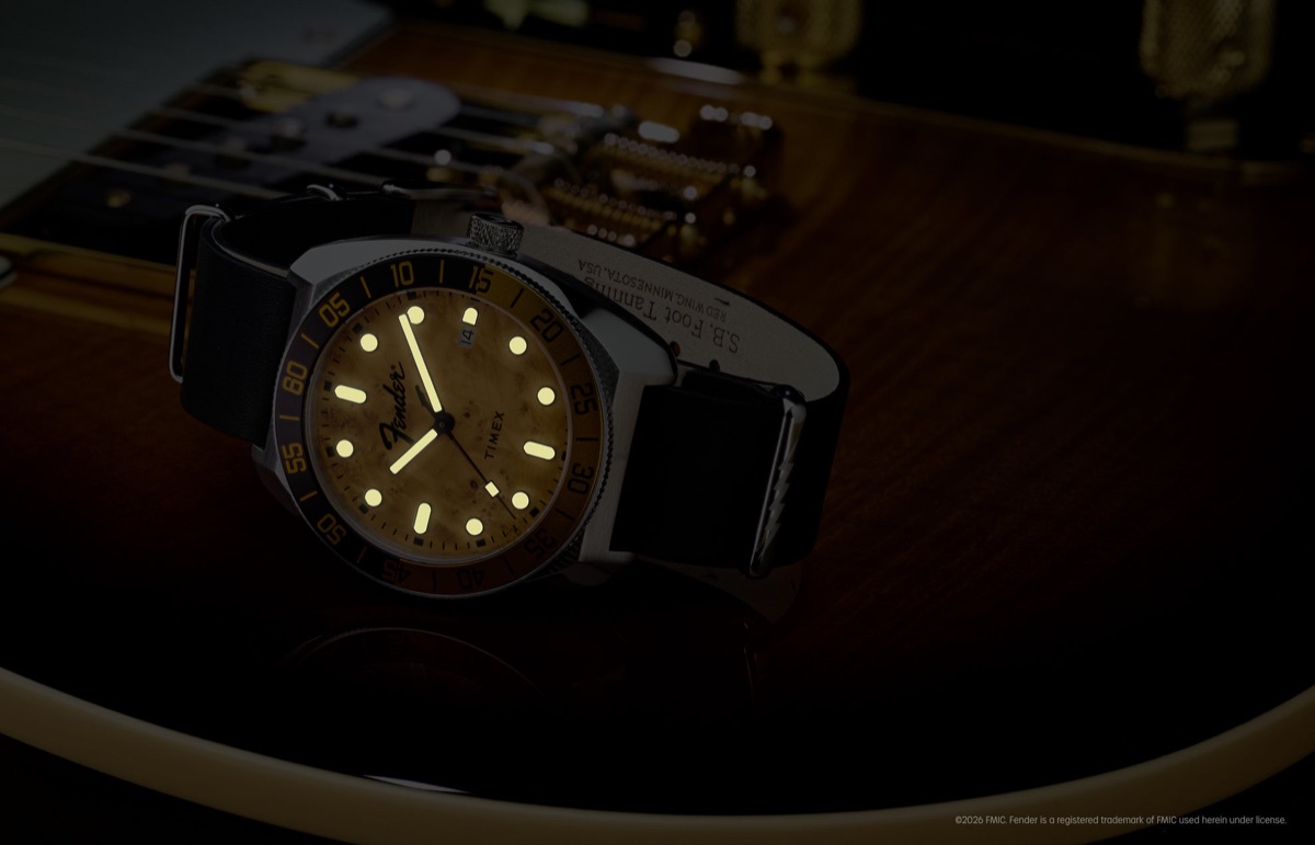 Fender x Timex Automatic with illuminated hands and hour markers displayed on a Fender guitar in low light.