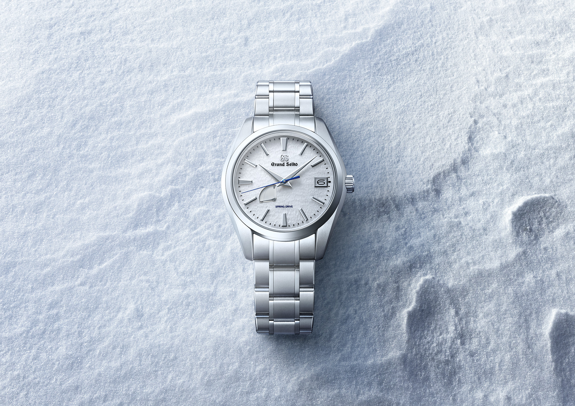 Grand Seiko SBGA211 Snowflake: A titán, a Spring Drive és a Hotaka-hegység hava Grand Seiko SBGA211 Snowflake titán fémszíjjal, szél fodrozta hóban fekve