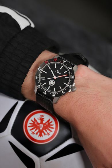 Sinn őszi újdonságok: jubileumi űrkronográf és három frankfurti különkiadás Sinn 105 Eintracht csuklón, a háttérben az Eintracht Frankfurt címere