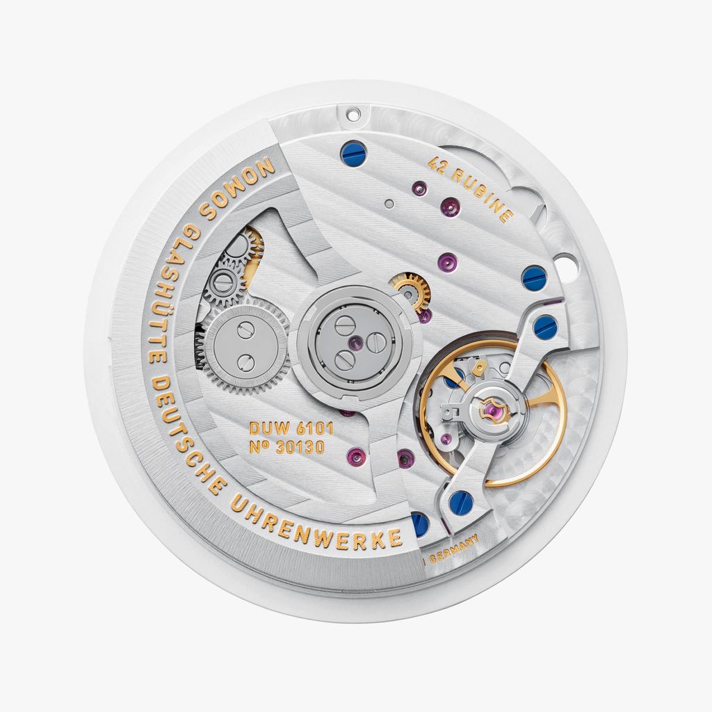 Jégkék Metro új kézi felhúzású kaliberrel: bemutatkozik a Nomos DUW 4701 Case back view of the DUW 6101 watch movement with engraved bridges, blue screws, and balance spring visible.
