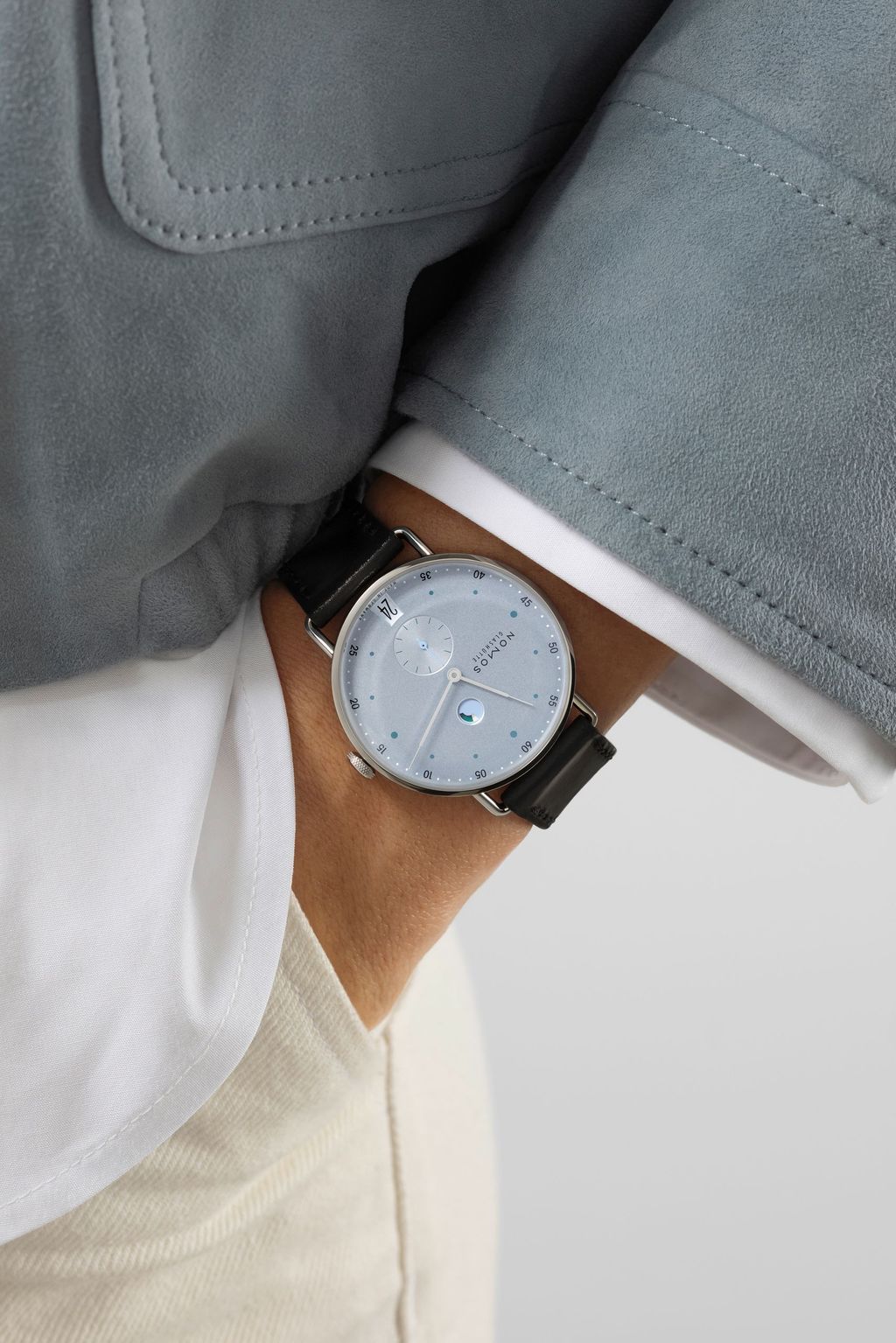 Jégkék Metro új kézi felhúzású kaliberrel: bemutatkozik a Nomos DUW 4701 Metro watch with ice blue dial on a wrist, black strap, visible date and power reserve displays.