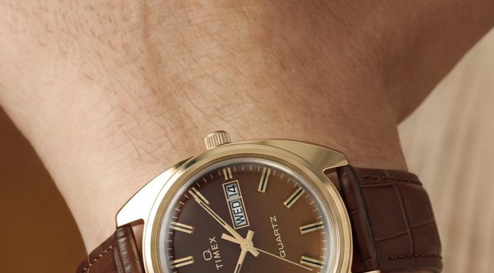 Timex 1978 Day Date Fumé Reissue: füstös barna számlap, 37 mm-es acéltok TW2Y87200 Wrist close-up of the Timex 1978 Day Date Fumé Reissue with a gold-tone case, brown leather strap, and day-date display.