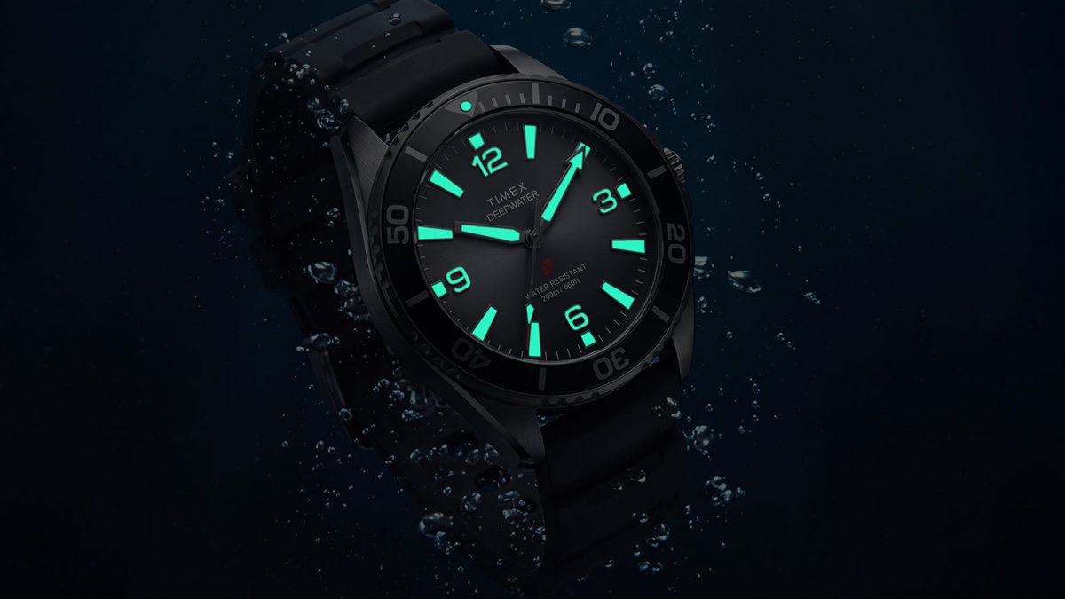 TW3A02000 Angled view of the Deepwater Arctic 200 watch with glowing aqua hands and hour markers amid underwater bubbles.