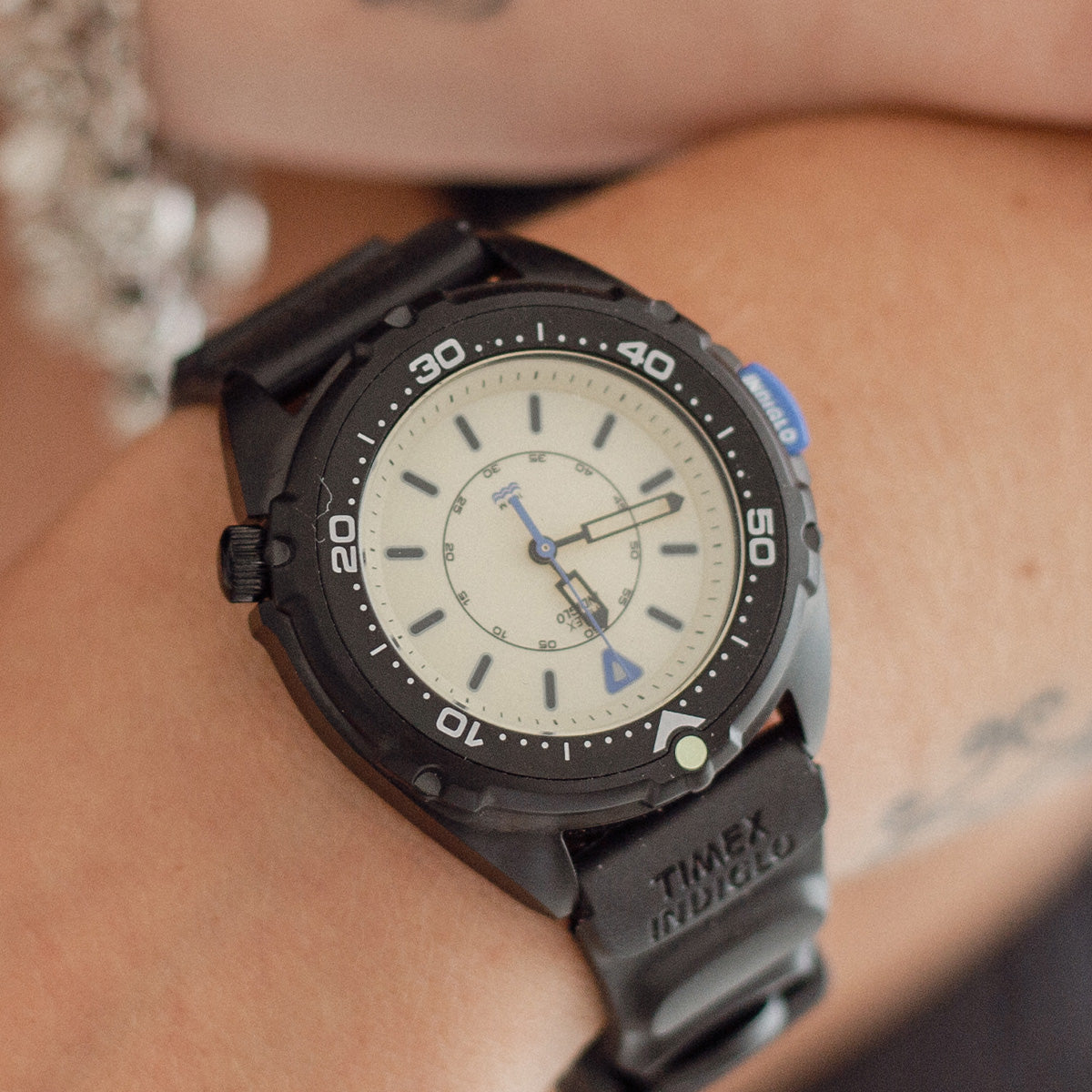 Feketébe öltözött a Timex Intrepid x Dimepiece: itt a 36 mm-es Blackout Edition TW6A19800 Close-up of the Timex Intrepid x Dimepiece ‘Blackout’ Edition on a wrist, showing its cream dial, black bezel and blue accents.