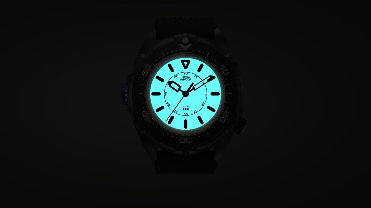 Feketébe öltözött a Timex Intrepid x Dimepiece: itt a 36 mm-es Blackout Edition TW6A19800 Timex Intrepid x Dimepiece ‘Blackout’ Edition with its dial illuminated turquoise by the INDIGLO backlight against a dark background.